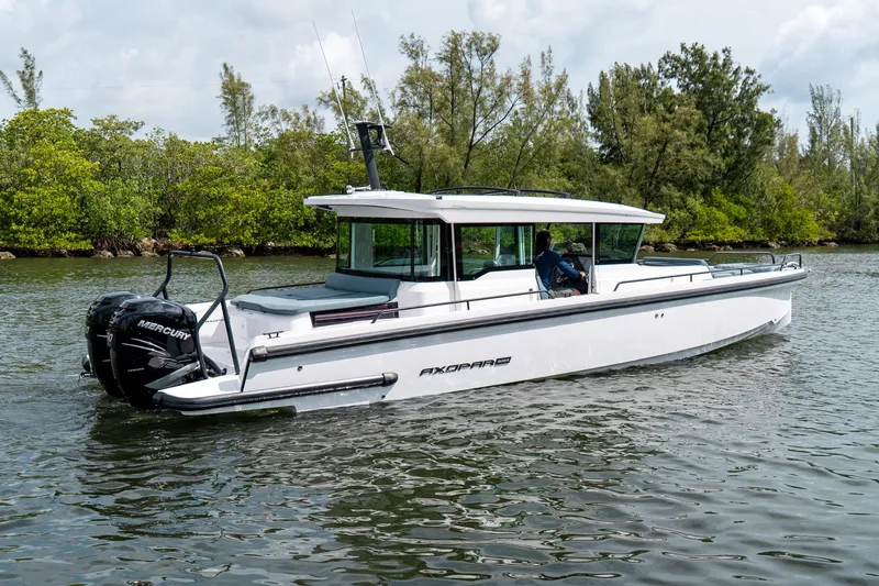 Slide: The Image of 2022 Axopar 37 XC Cross Cabin boat cruising on a calm river with lush greenery. - 3