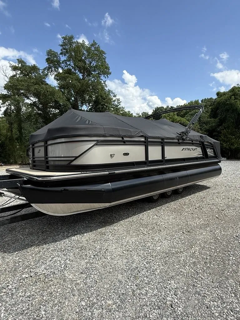 The Image of Starcraft SLS-3 pontoon boat 2025 on gravel lot, covered, blue sky. - 1