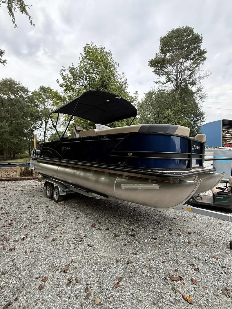 The Image of 2026 Sylvan L-3 DLZ pontoon boat on trailer, parked outdoors. - 1