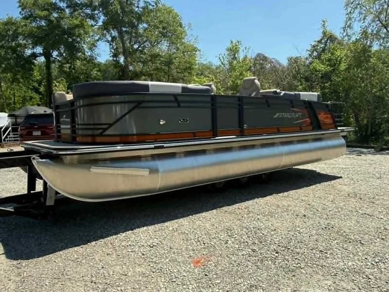 Slide: The Image of 2025 Starcraft SLS-3 pontoon boat on gravel lot, surrounded by trees. - 22