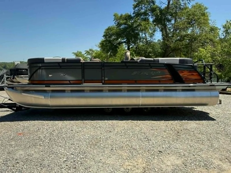 Slide: The Image of 2025 Starcraft SLS-3 pontoon boat parked on gravel surface. - 23