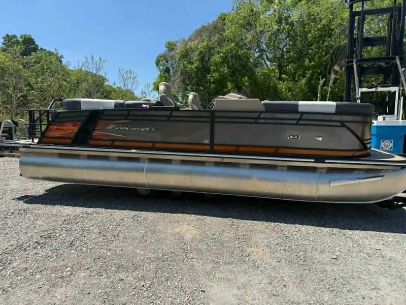 Slide: The Image of 2025 Starcraft SLS-3 pontoon boat on gravel lot, surrounded by trees. - 4