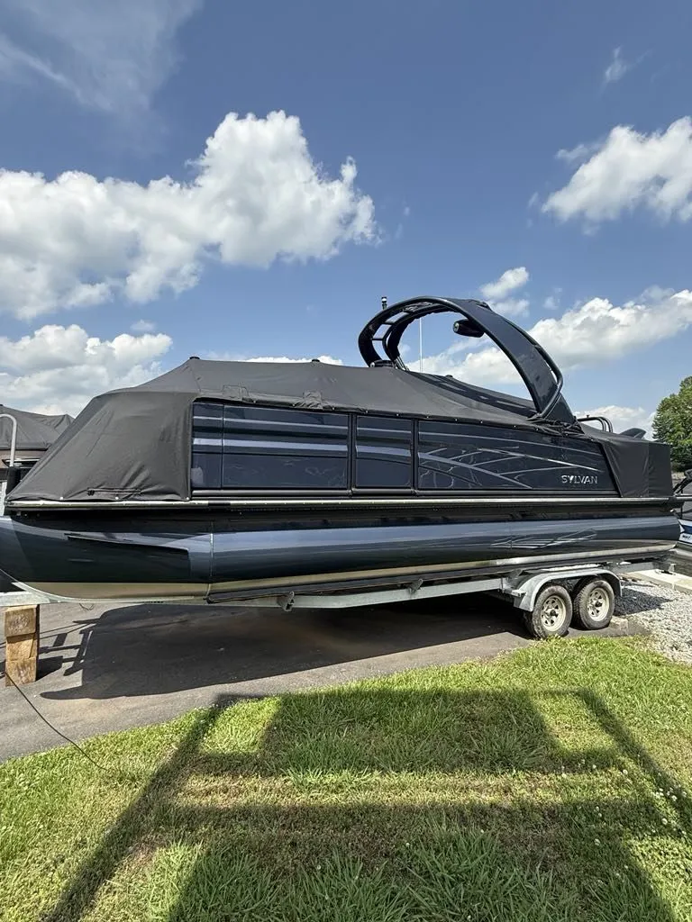 The Image of 2025 Sylvan G3 DLZ Bar pontoon boat on trailer, blue sky. - 1