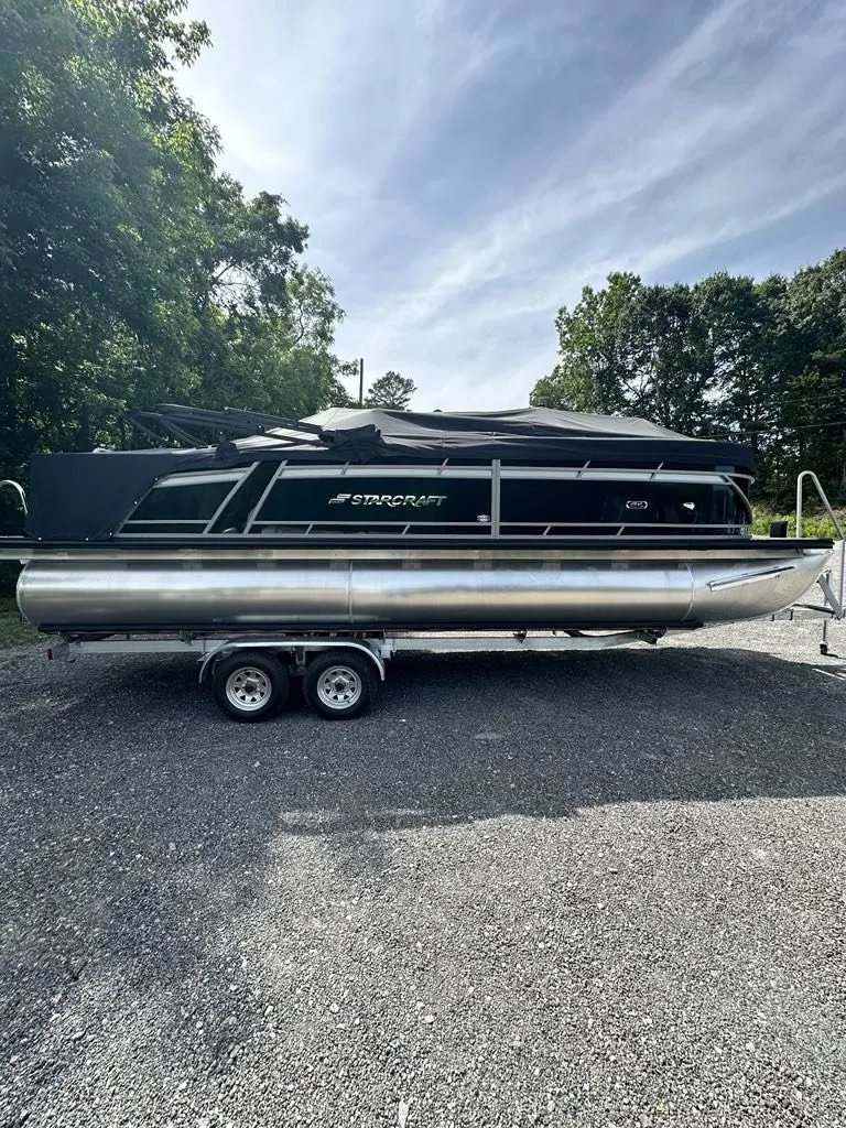 The Image of 2024 Starcraft CX 23 Q DH pontoon boat on trailer outdoors. - 1