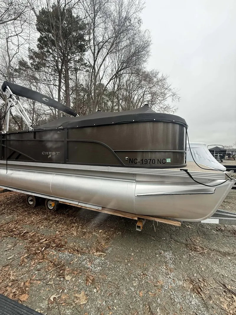 Slide: The Image of 2024 Crest Classic LX 200 pontoon boat on trailer outdoors. - 14