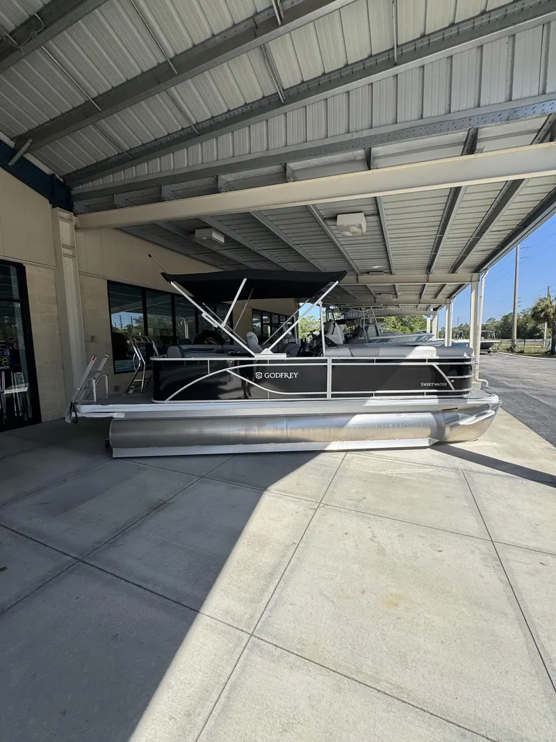 Slide: The Image of 2026 Sweetwater SW2086CSE pontoon boat under a covered area. - 18