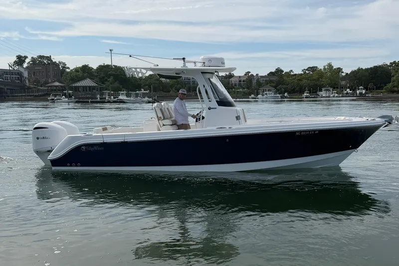 The Image of 2021 Edgewater 262CC boat on calm water with Yamaha engine, near shoreline. - 0