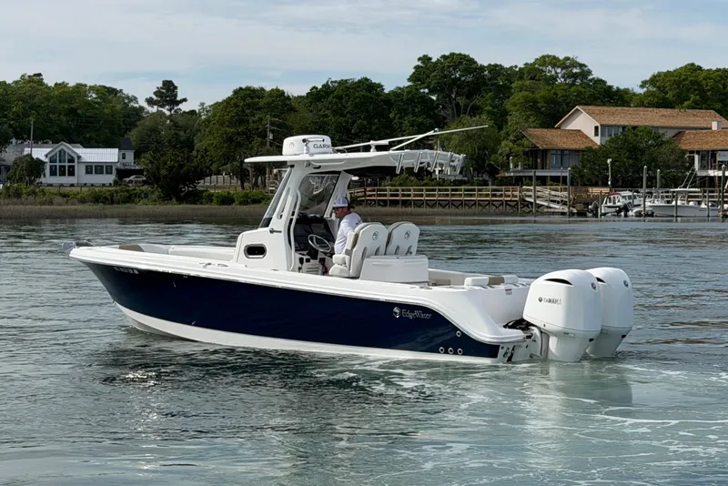 Slide: The Image of 2021 Edgewater 262CC boat cruising on a calm lake near waterfront homes. - 10