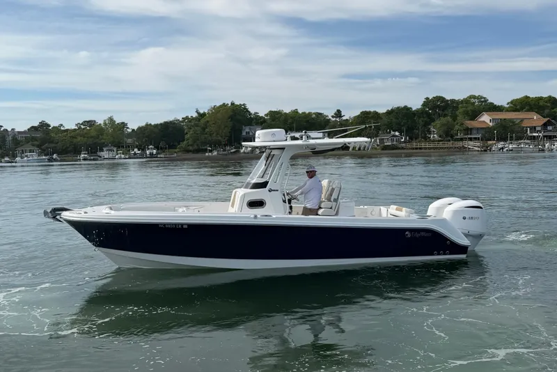 Slide: The Image of 2021 Edgewater 262CC boat cruising on calm waters with scenic background. - 11