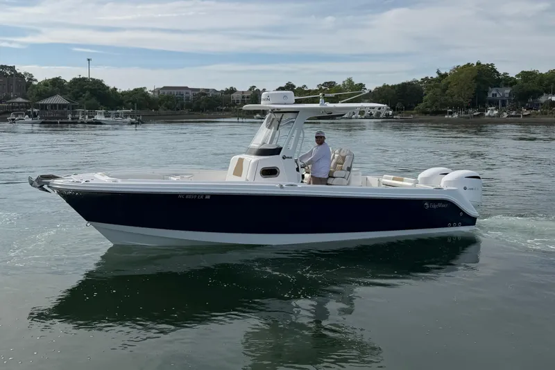 Slide: The Image of 2021 Edgewater 262CC boat cruising on calm waters with a person at the helm. - 13