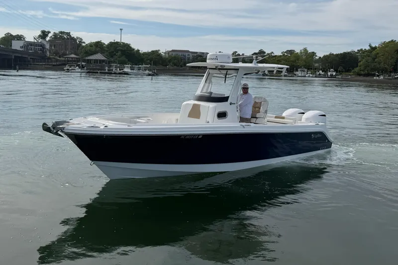 Slide: The Image of 2021 Edgewater 262CC boat cruising on calm waters near a marina. - 14