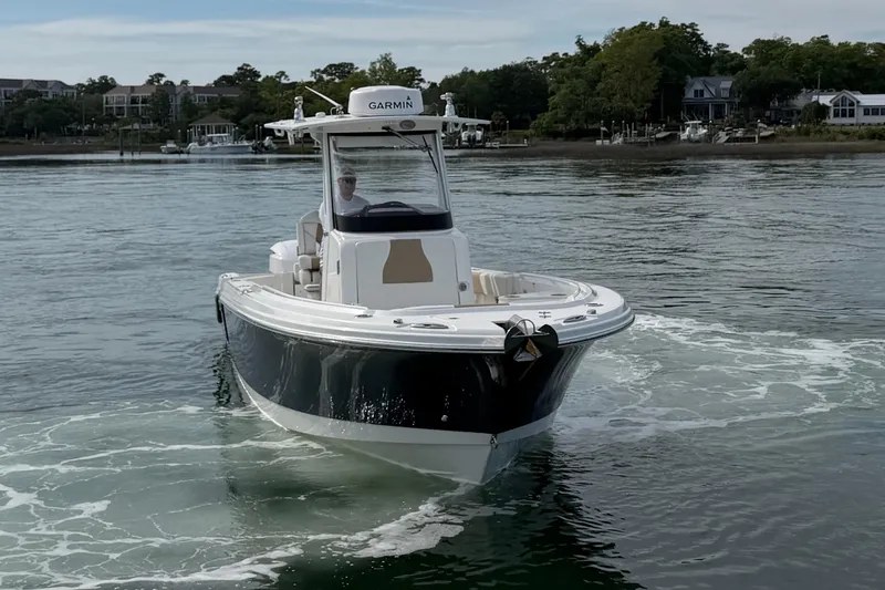 Slide: The Image of 2021 Edgewater 262CC boat cruising on calm water near a shoreline. - 17