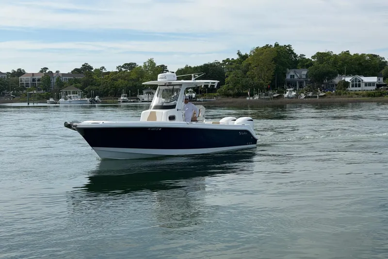 Slide: The Image of 2021 Edgewater 262CC boat cruising on calm water near a scenic shoreline. - 19