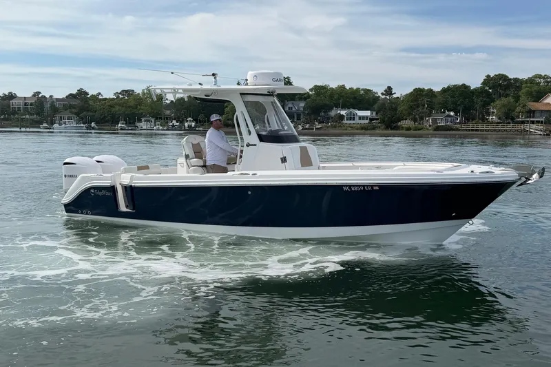 Slide: The Image of 2021 Edgewater 262CC boat cruising on a calm lake with scenic background. - 2
