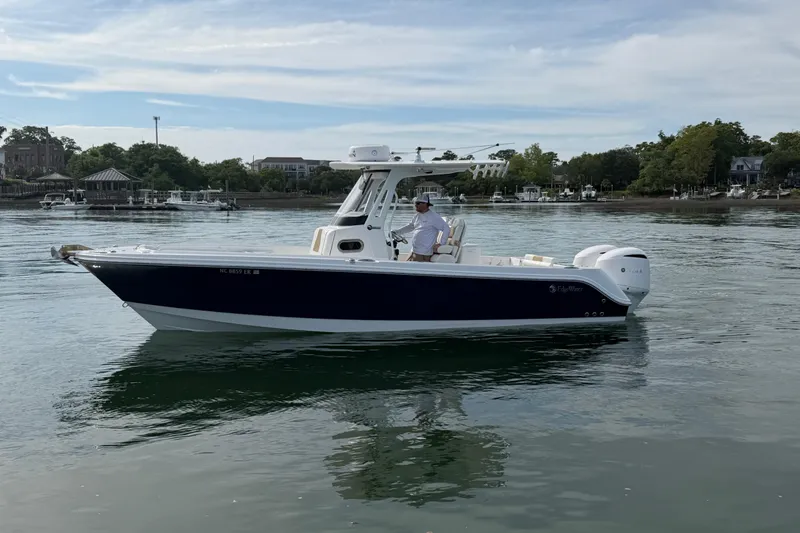Slide: The Image of 2021 Edgewater 262CC boat on calm water, with scenic shoreline background. - 22