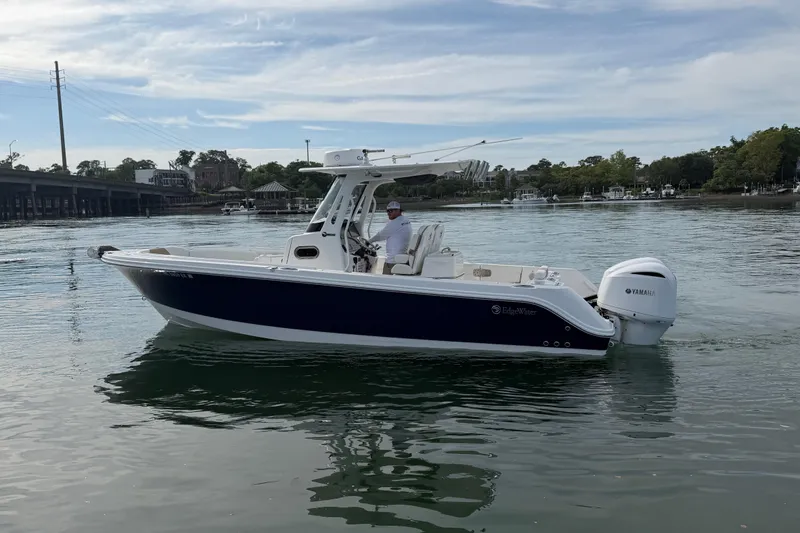 Slide: The Image of 2021 Edgewater 262CC boat on calm water with Yamaha engine, under a clear sky. - 24
