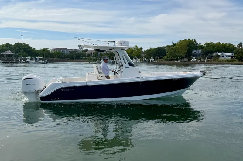 Slide: The Image of 2021 Edgewater 262CC boat on calm water, with scenic shoreline background. - 3