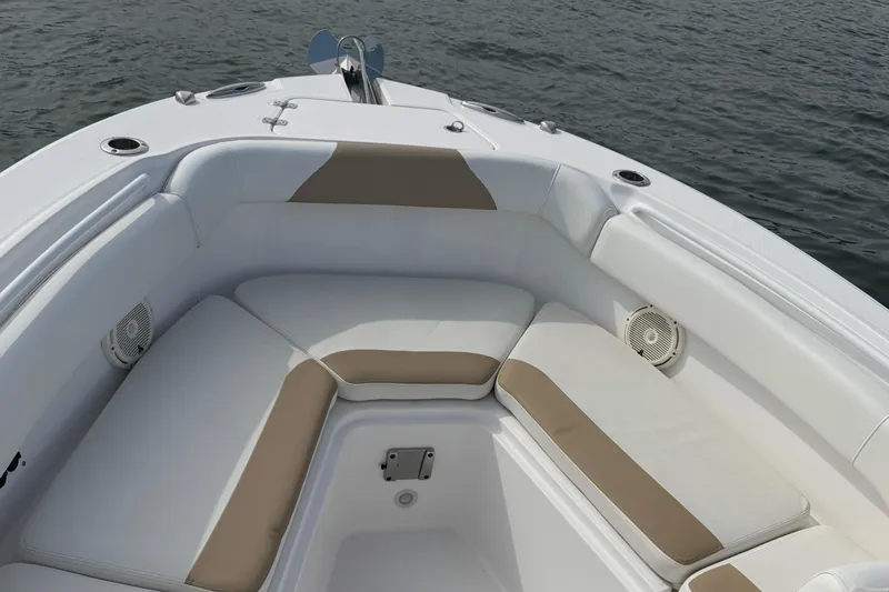 Slide: The Image of 2021 Edgewater 262CC boat interior with cushioned seating, on calm water. - 33