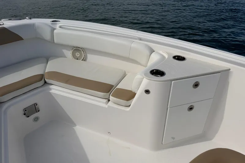 Slide: The Image of 2021 Edgewater 262CC boat interior with cushioned seating and cup holders, near water. - 34