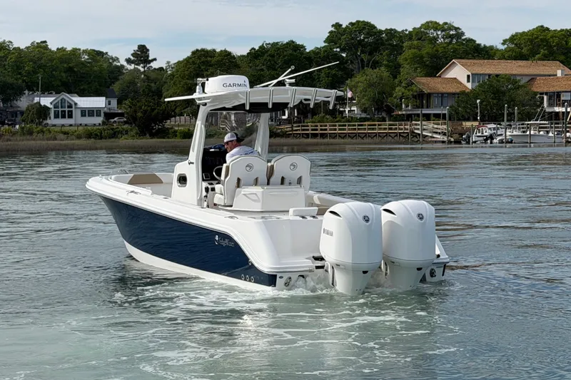 Slide: The Image of 2021 Edgewater 262CC boat cruising on calm water near shoreline houses. - 5