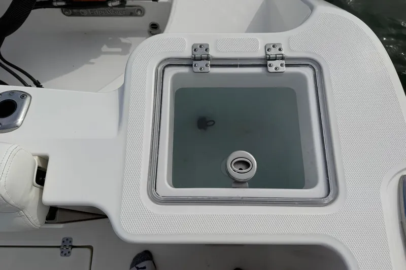 Slide: The Image of Livewell on 2021 Edgewater 262CC boat, featuring a transparent lid and secure hinges. - 53