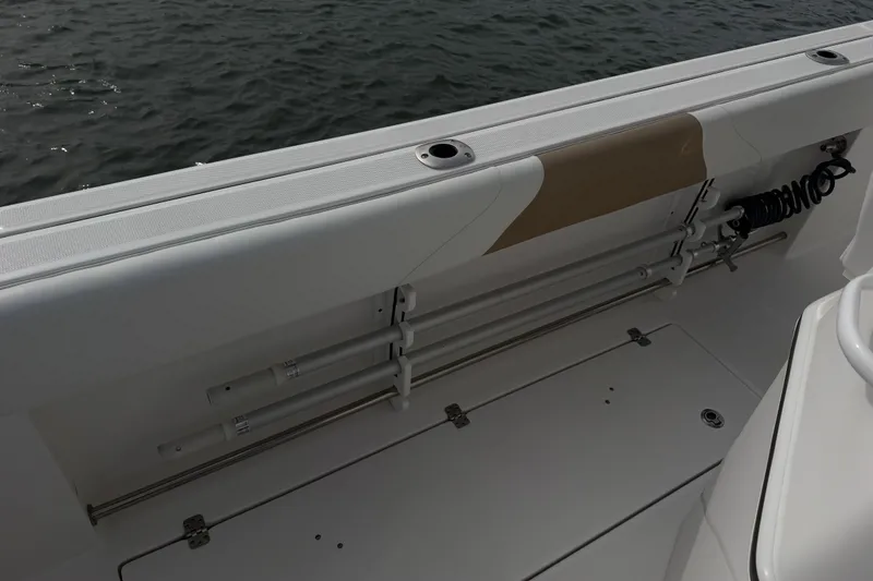 Slide: The Image of 2021 Edgewater 262CC boat interior with rod holders and storage, near water. - 57
