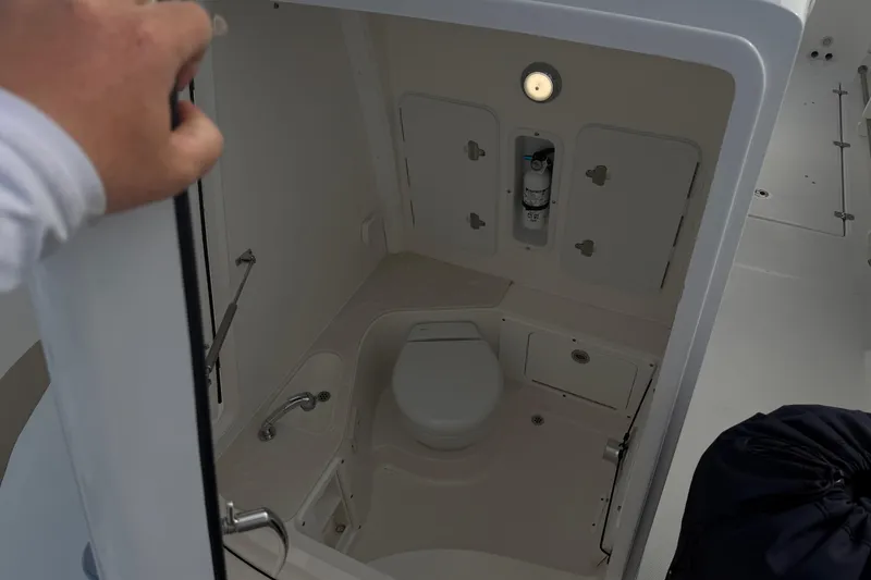 Slide: The Image of 2021 Edgewater 262CC boat interior with compact marine toilet and storage compartments. - 58