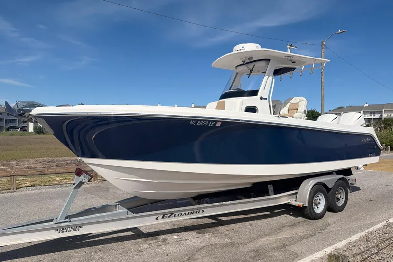 Slide: The Image of 2021 Edgewater 262CC boat on trailer, blue and white design, parked outdoors. - 62
