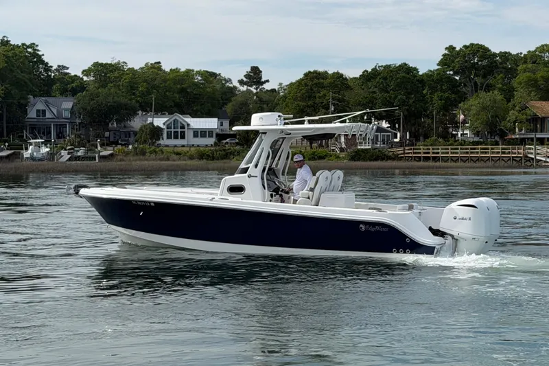 Slide: The Image of 2021 Edgewater 262CC boat cruising on a calm river near waterfront homes. - 9