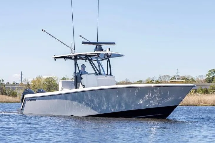 Slide: The Image of 2022 Contender 32 ST boat cruising on a calm waterway under clear skies. - 11