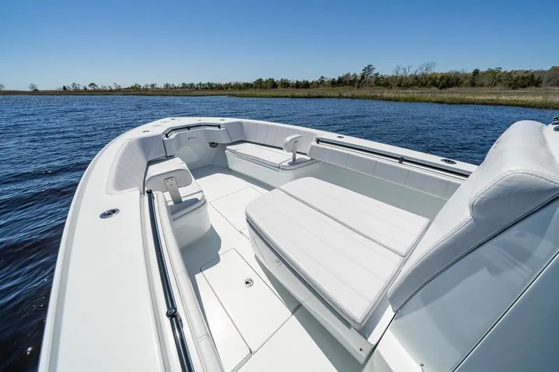 Slide: The Image of 2022 Contender 32 ST boat interior with white seating on a calm lake. - 12