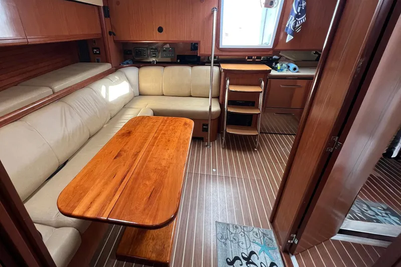 Slide: The Image of 2007 Luhrs 41 Hardtop interior with beige seating, wooden table, and compact kitchen area. - 4