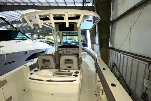 Slide: The Image of 2024 Boston Whaler 280 Outrage boat interior with seating and console in a marina. - 4
