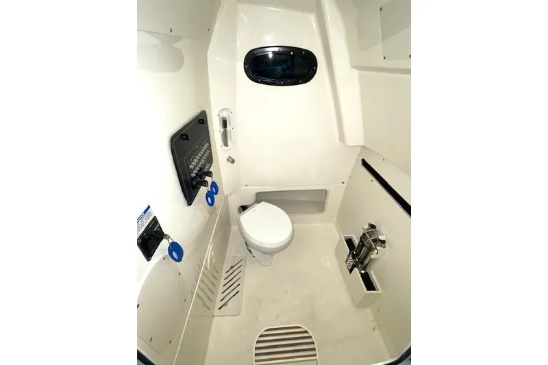Slide: The Image of 2024 Boston Whaler 280 Outrage interior cabin with toilet and control panel. - 6