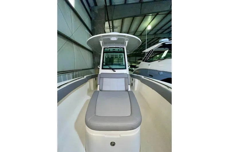 Slide: The Image of 2024 Boston Whaler 280 Outrage boat interior with cushioned seating in a warehouse. - 8