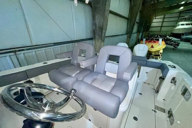 Slide: The Image of 2024 Boston Whaler 280 Outrage interior with plush seating and steering wheel in a storage facility. - 9