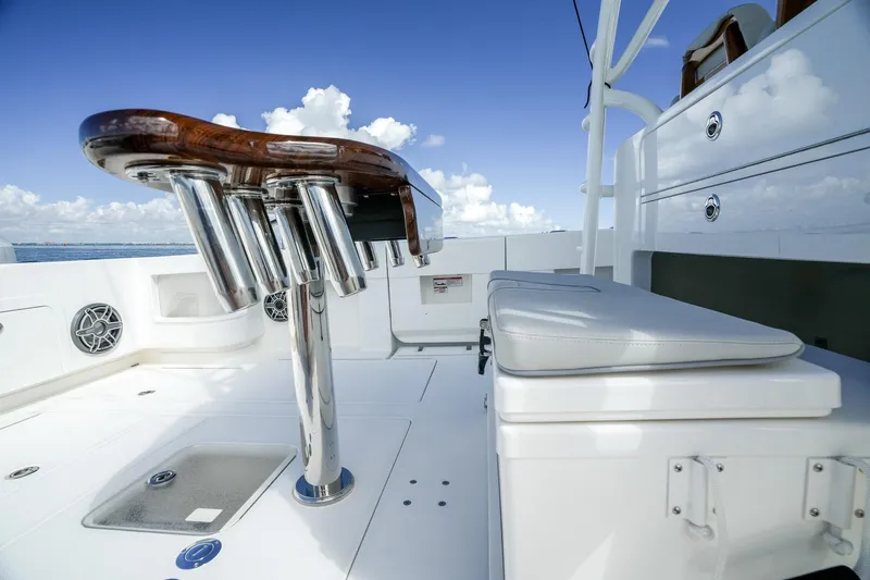 Slide: The Image of 2024 SeaVee 400Z boat deck with rod holders and cushioned seating under a clear sky. - 14