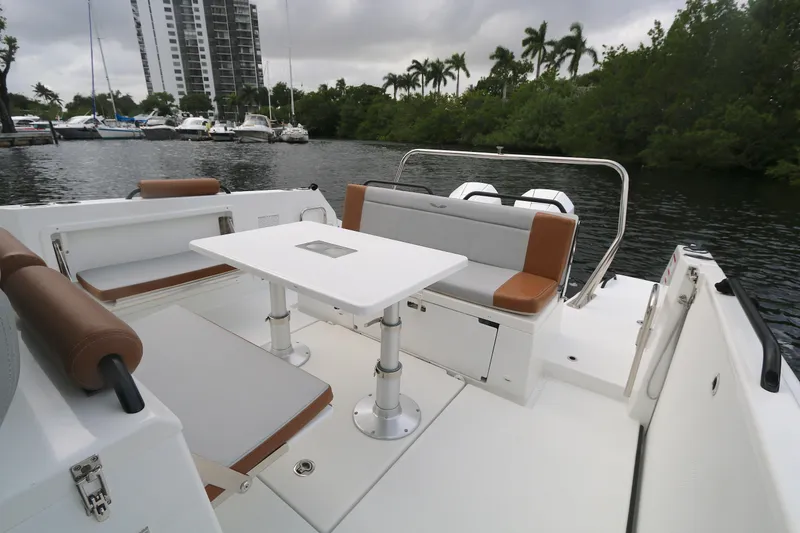Slide: The Image of 2022 Beneteau Flyer 9 SPACEdeck boat interior with seating and table, docked near lush greenery. - 10