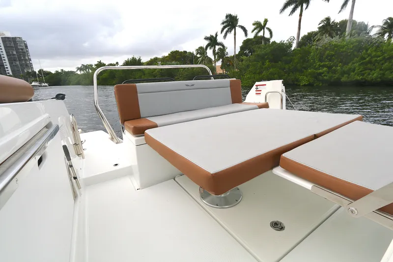 Slide: The Image of 2022 Beneteau Flyer 9 SPACEdeck boat with cushioned seating, docked near lush greenery. - 13