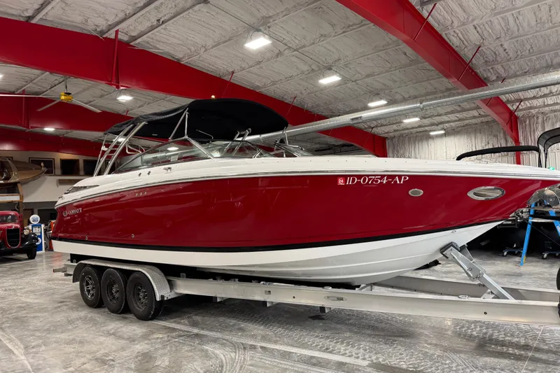 The Image of 2007 Cobalt 302 boat with red hull on a trailer in a spacious indoor facility. - 1