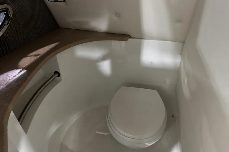 Slide: The Image of Compact bathroom in a 2007 Cobalt 302 boat, featuring a white toilet and countertop. - 11