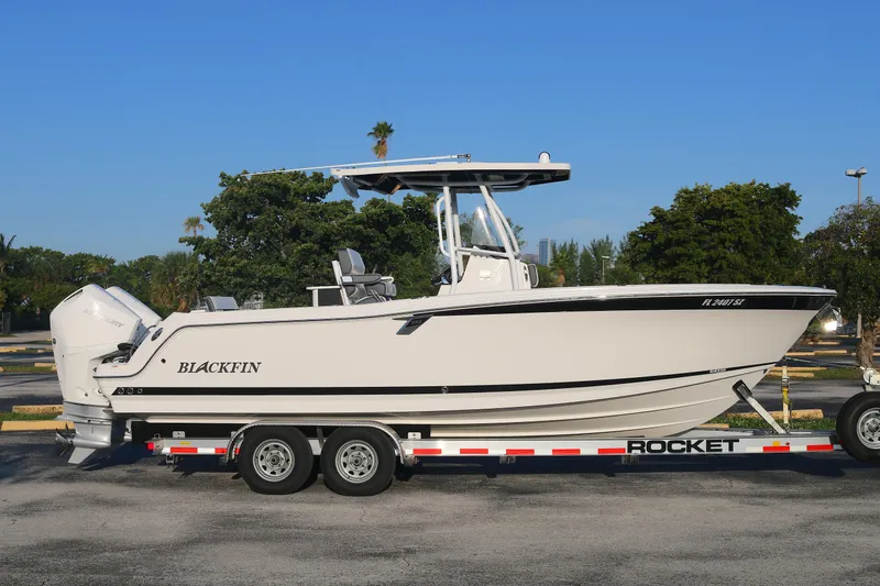 The Image of 2021 BLACWATER 252CC boat on trailer, parked outdoors with trees in background. - 0