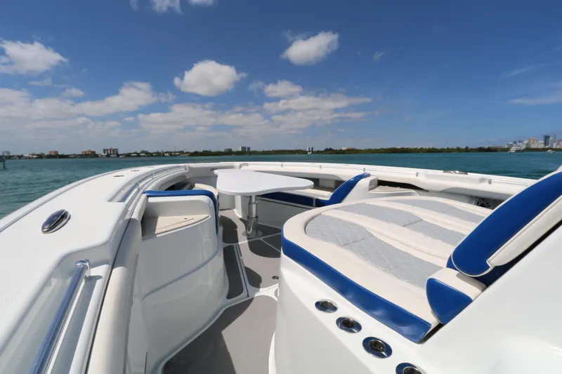 Slide: The Image of 2021 Yellowfin 54 Offshore boat interior with seating and table, under a clear blue sky. - 12