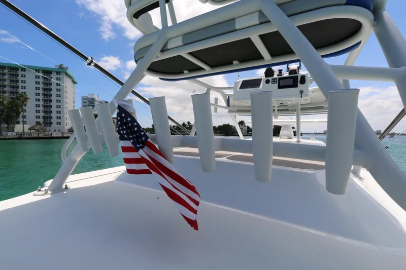Slide: The Image of 2021 Yellowfin 54 Offshore boat deck with American flag, overlooking waterfront buildings. - 16