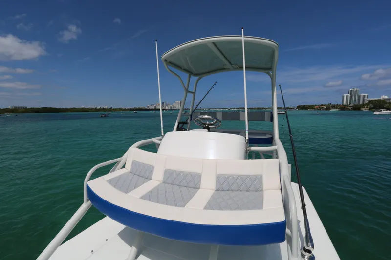 Slide: The Image of 2021 Yellowfin 54 Offshore boat on turquoise water, clear sky, city skyline in background. - 17