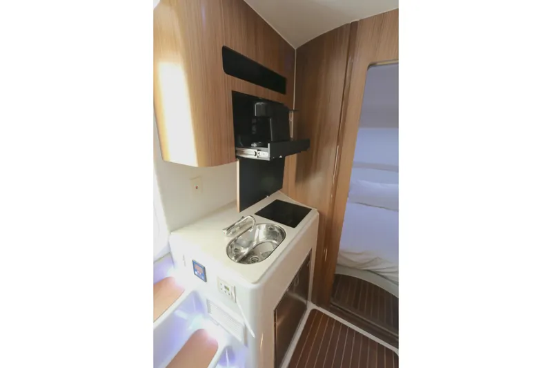 Slide: The Image of 2021 Yellowfin 54 Offshore yacht interior kitchenette with sink and wooden cabinetry. - 18