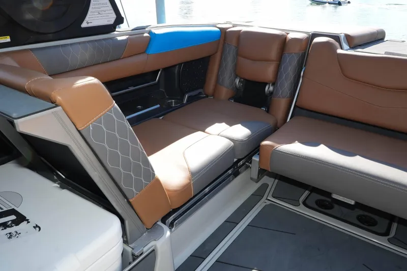 Slide: The Image of 2020 Malibu M240 boat interior with brown and gray seating, featuring diamond stitching. - 11