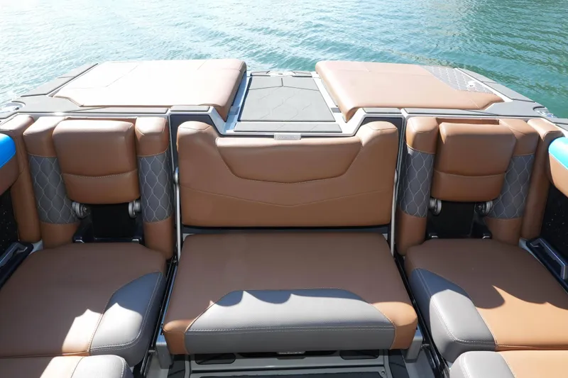 Slide: The Image of 2020 Malibu M240 boat interior with brown leather seating and water backdrop. - 15