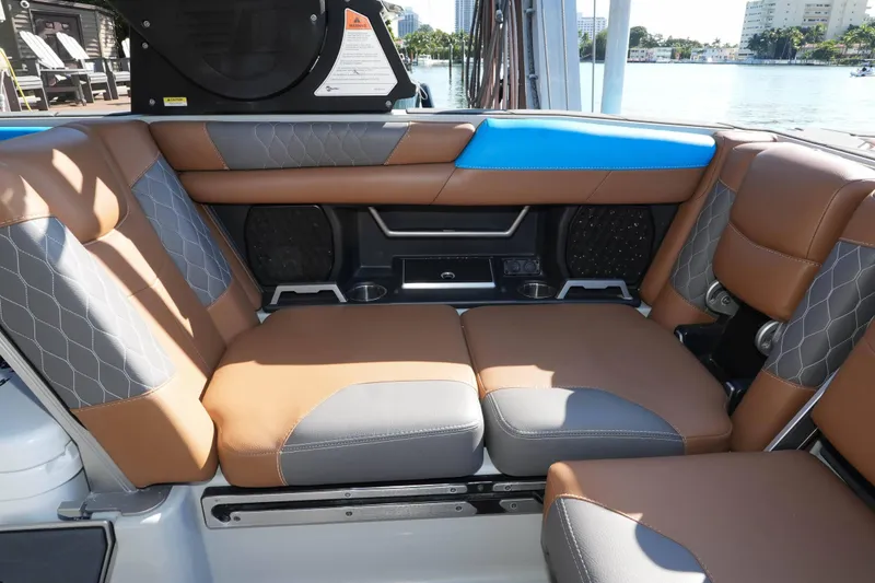 Slide: The Image of 2020 Malibu M240 boat interior with brown and gray seating, blue accents, and waterfront view. - 16