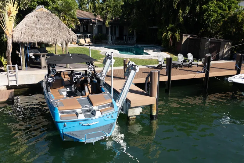 Slide: The Image of Blue 2020 Malibu M240 boat docked by a luxurious waterfront property with a pool. - 19
